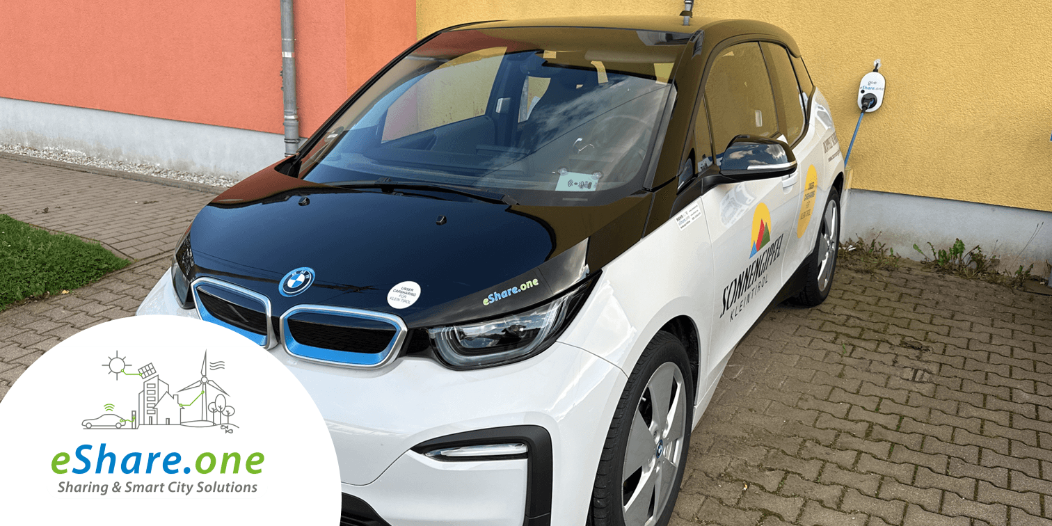 schwarz-weißes Fahrzeug des Partners eShare.one auf einem Parkplatz vor einer orange-roten Mauer copyright Next eShare.one GmbH