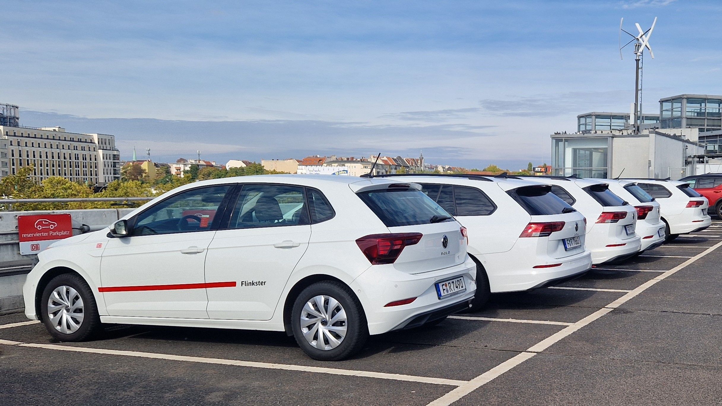 Flinkster carsharing vehicles in reserved parking spaces, ready for use, with the city skyline in the background.
