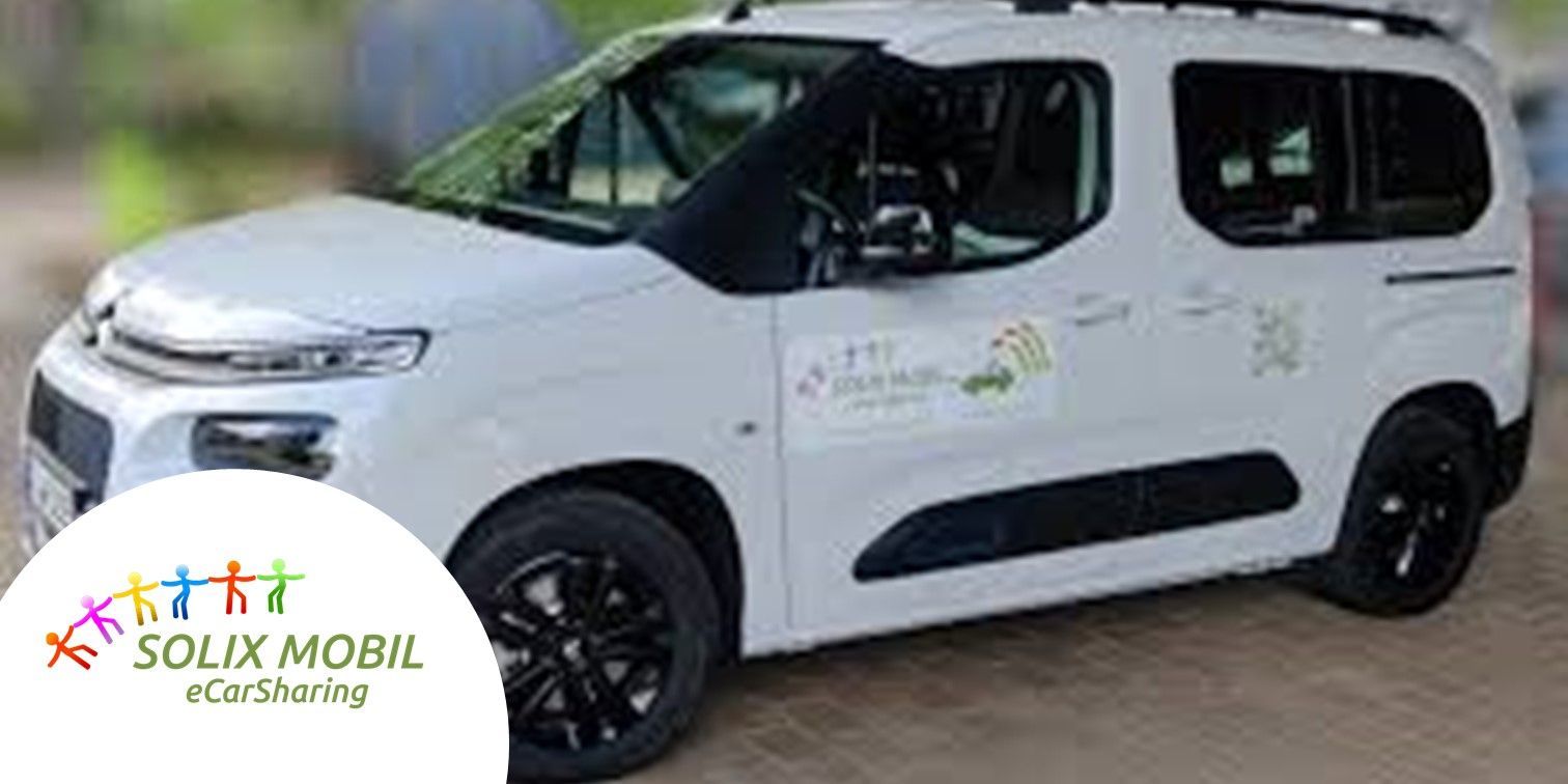 schwarz-weißes Fahrzeug des Partners eShare.one auf einem Parkplatz vor einer orange-roten Mauer copyright SOLIX