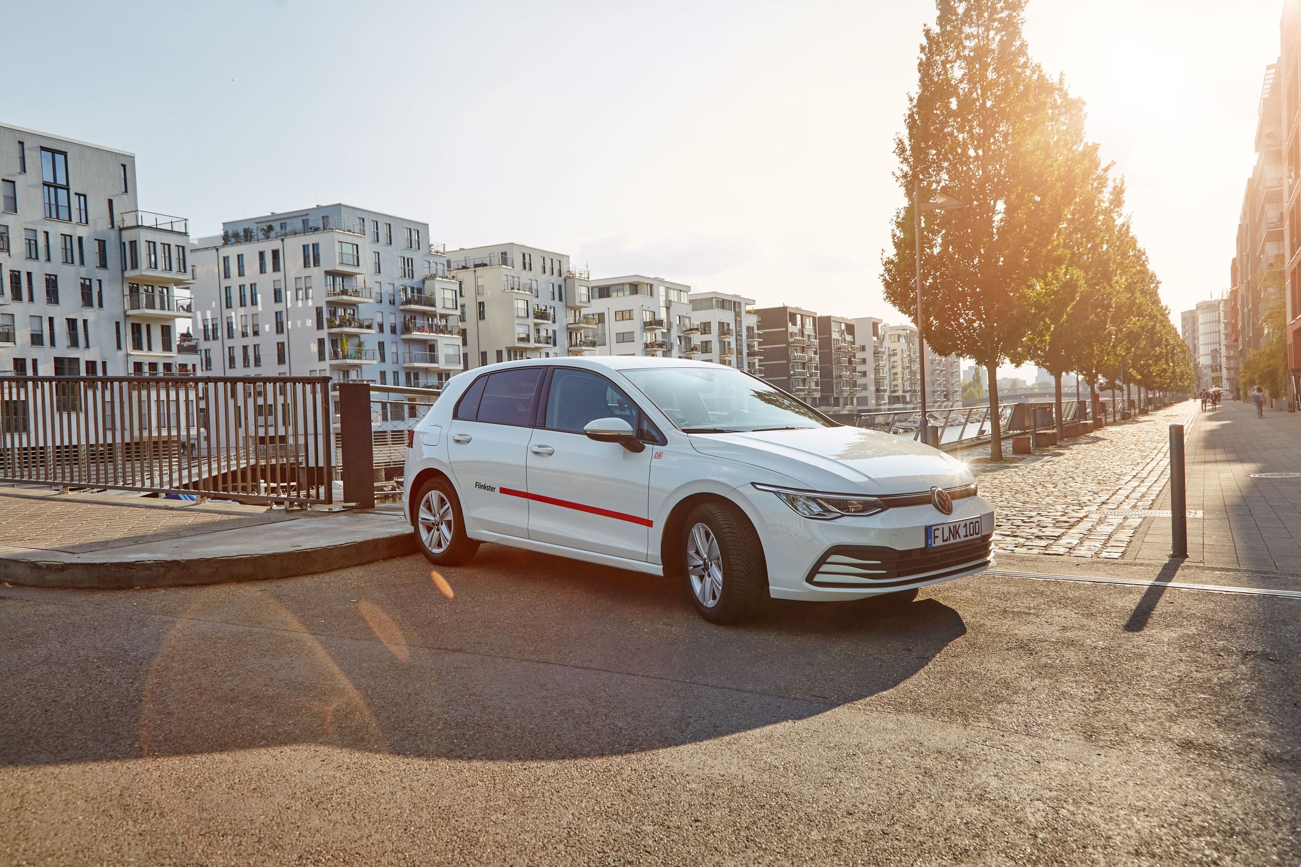 Geparktes Flinkster-Auto in einem modernen Stadtviertel bei Sonnenuntergang.